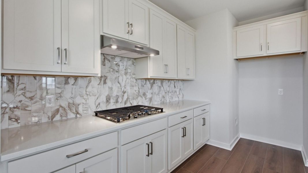 Kitchen white cabinets, quartz countertop, tile backsplash, and gas cooktop