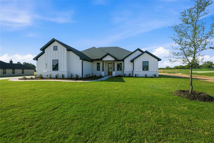 Modern farmhouse with board and batten siding and a front lawn Modern farmhouse with board and batten siding and a front lawn