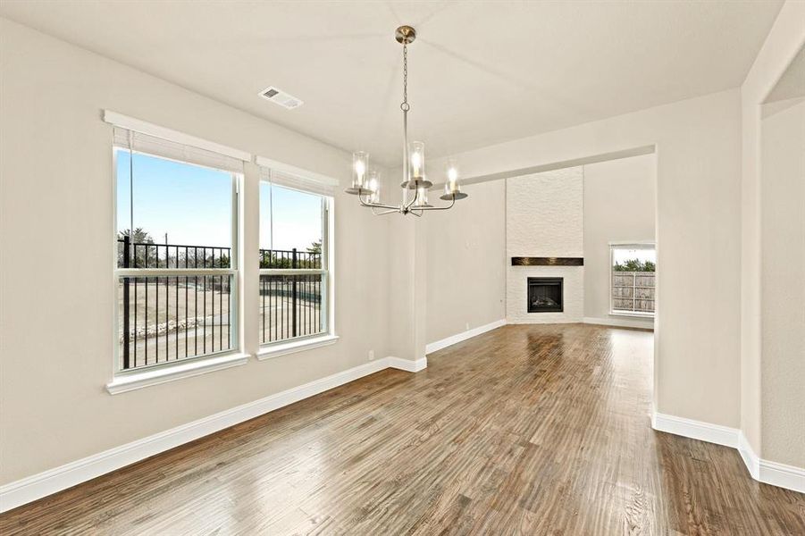 Unfurnished living room featuring a large fireplace, dark wood-style flooring, and a chandelier