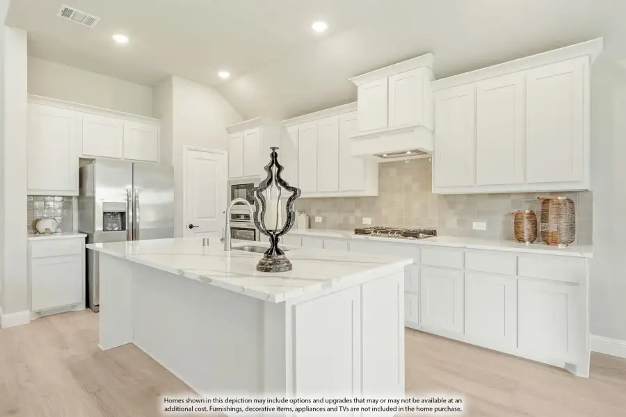 Kitchen with white shaker cabinets, marble island, tile backsplash, and stainless steel appliances on light wood floors. Kitchen with white shaker cabinets, marble island, tile backsplash, and stainless steel appliances on light wood floors.
