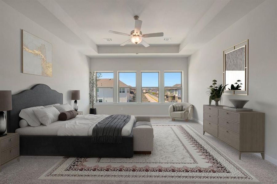 Bedroom with carpet floors, a raised ceiling, and a ceiling fan