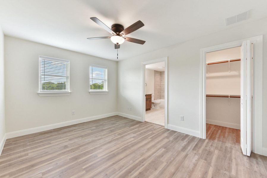 Bedroom 2 featuring light wood finished style floors, visible vents, connected bathroom, a walk in closet, and a closet