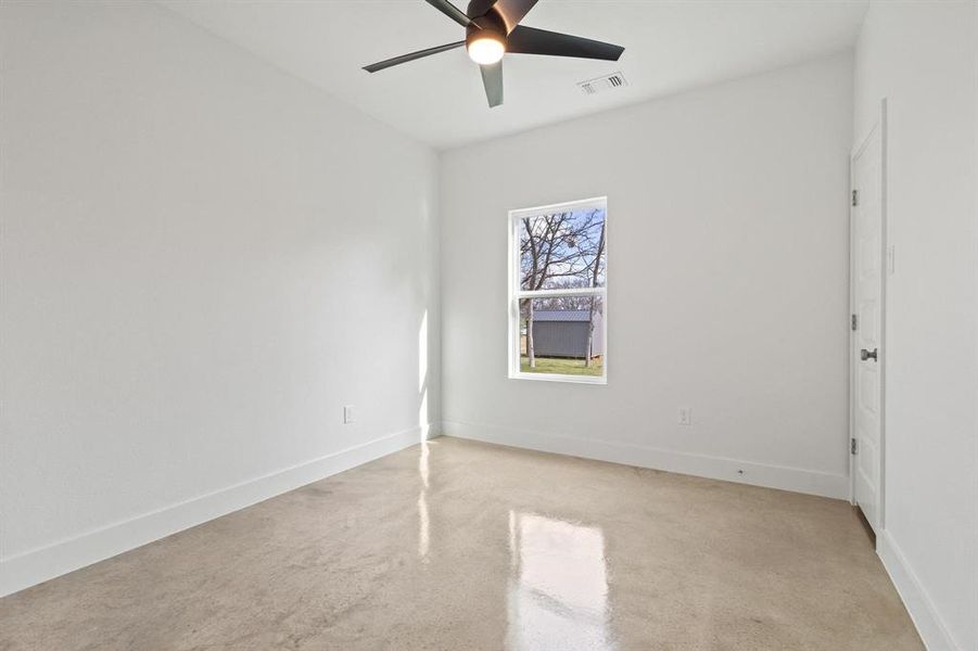 Empty room with ceiling fan and finished concrete flooring
