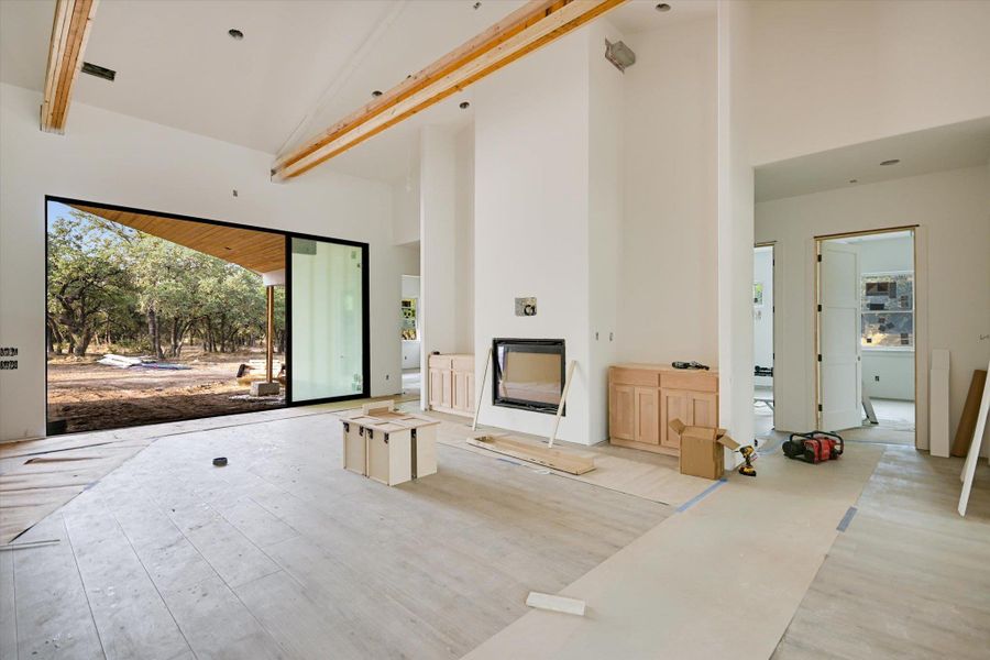 Unfurnished living room featuring high vaulted ceiling, wood finished floors, and beam ceiling