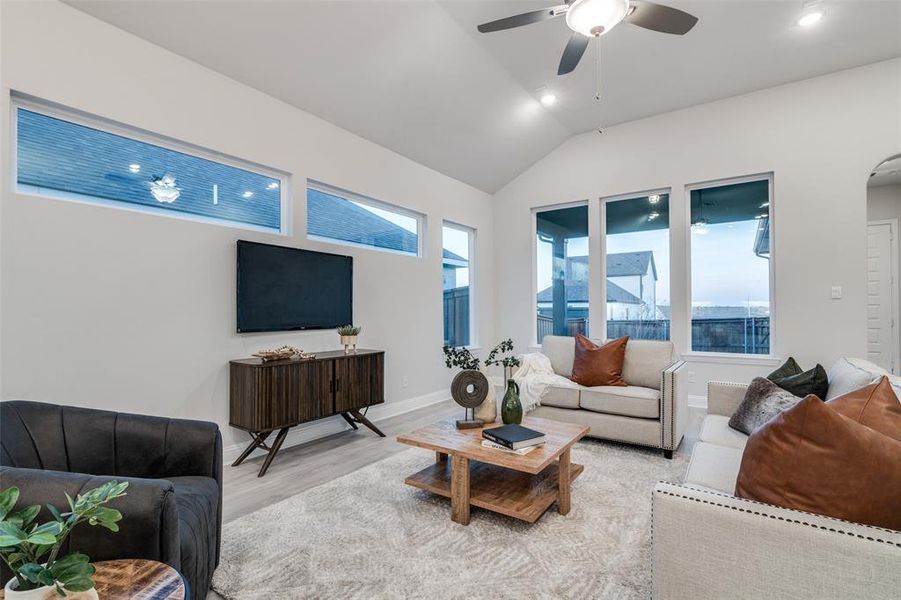 Living room with ceiling fan, lofted ceiling, and light hardwood / wood-style flooring