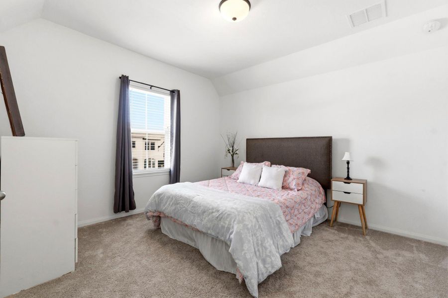Cozy bedroom with neutral tones, featuring natural light from a window with curtains.
