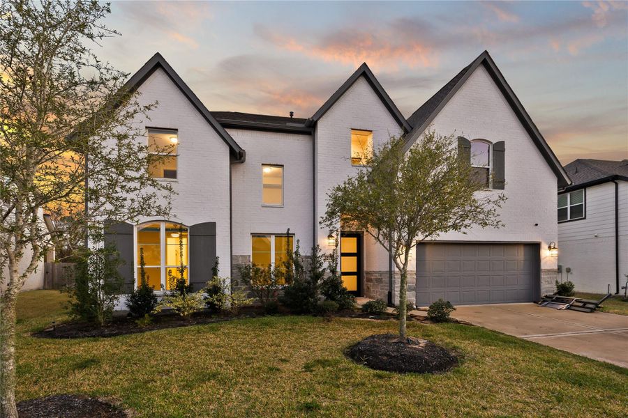 This elegant two-story home features a modern exterior with a combination of white brick and dark accents. It includes a spacious two-car garage, landscaped front yard, and large windows. The entrance is inviting, with a well-lit pathway and mature trees. Perfect for those seeking a stylish and comfortable living space. This elegant two-story home features a modern exterior with a combination of white brick and dark accents. It includes a spacious two-car garage, landscaped front yard, and large windows. The entrance is inviting, with a well-lit pathway and mature trees. Perfect for those seeking a stylish and comfortable living space.