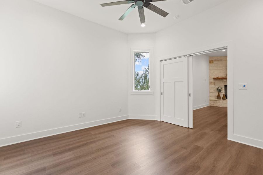 Unfurnished bedroom featuring wood finished floors, a fireplace, baseboards, ceiling fan, and recessed lighting Unfurnished bedroom featuring wood finished floors, a fireplace, baseboards, ceiling fan, and recessed lighting
