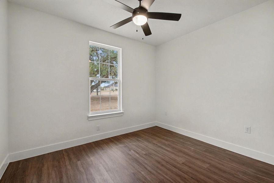 Spare room with dark wood-type flooring and ceiling fan