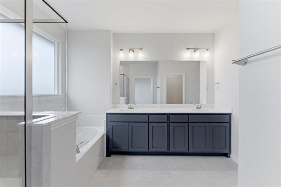 Spacious bathroom featuring a double vanity with ample cabinetry, a large integrated mirror, and dual light fixtures