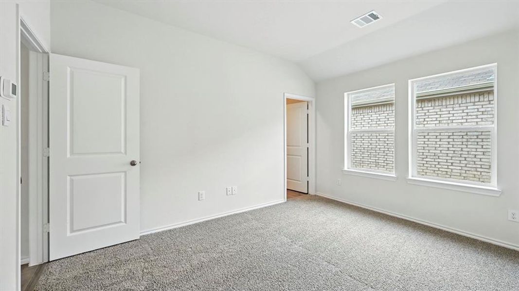 Carpeted room featuring two panel doors, two windows, and vaulted ceilings Carpeted room featuring two panel doors, two windows, and vaulted ceilings