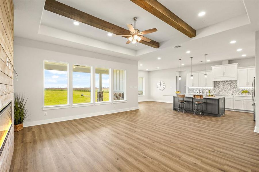 A pair of cedar beams add a warm and rustic feel to the elegant space. Notice how the LVP flooring continues throughout the entire living space, aiding in a seamless look and enhancing the open concept design.