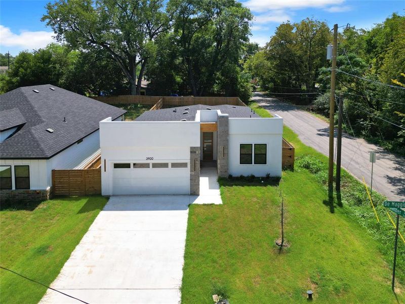 Contemporary house featuring a garage, stucco siding, driveway, and view of wooded area