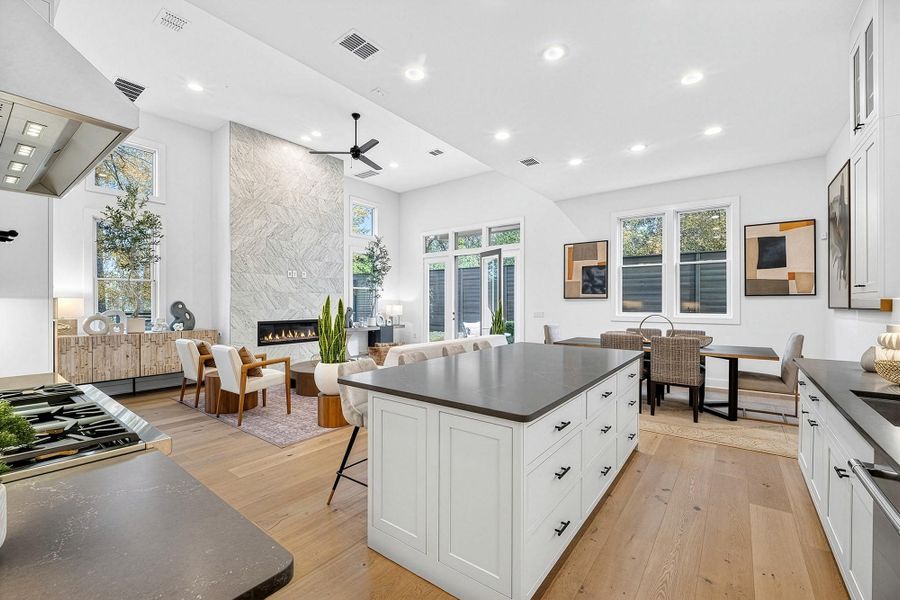 Kitchen featuring white cabinets, a breakfast bar, custom exhaust hood, a center island, and light wood-style floors
