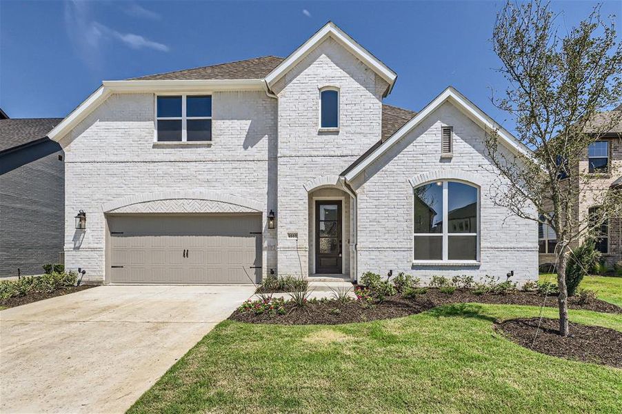 French country inspired facade with a front lawn and a garage