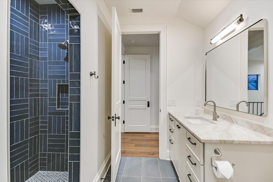 Bathroom with vanity, dark tile patterned flooring, and tiled shower Bathroom with vanity, dark tile patterned flooring, and tiled shower