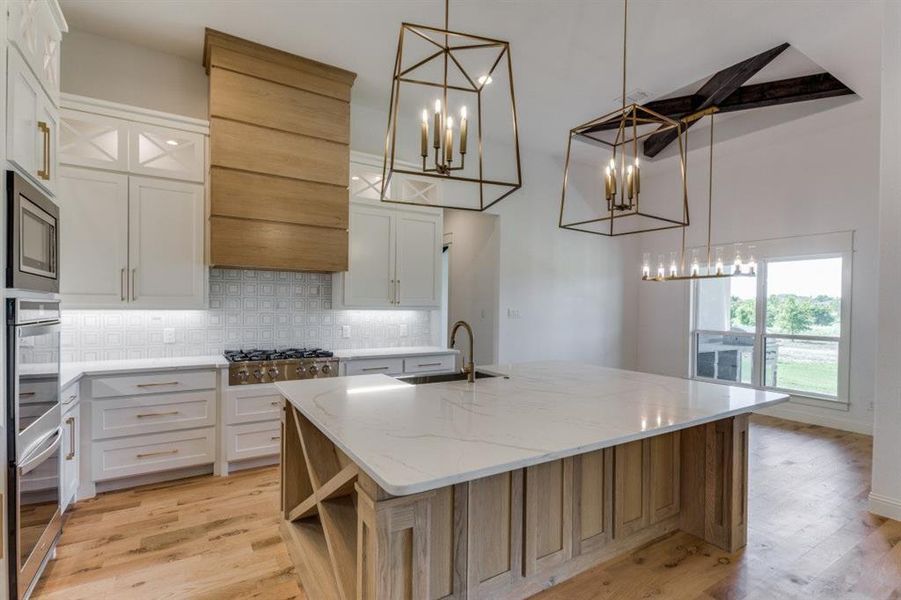 Kitchen featuring a center island with sink, sink, light hardwood / wood-style flooring, and white cabinets