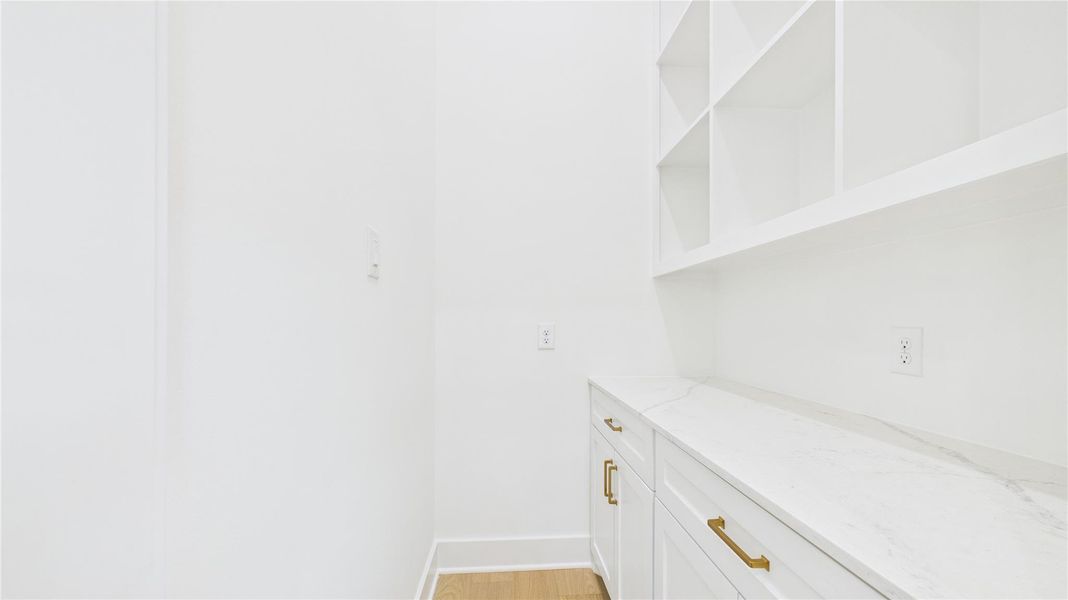 The butler's pantry features open shelves above, a quartz countertop, and built-ins - providing ample storage and a clean, modern look. No kitchen counter clutter.