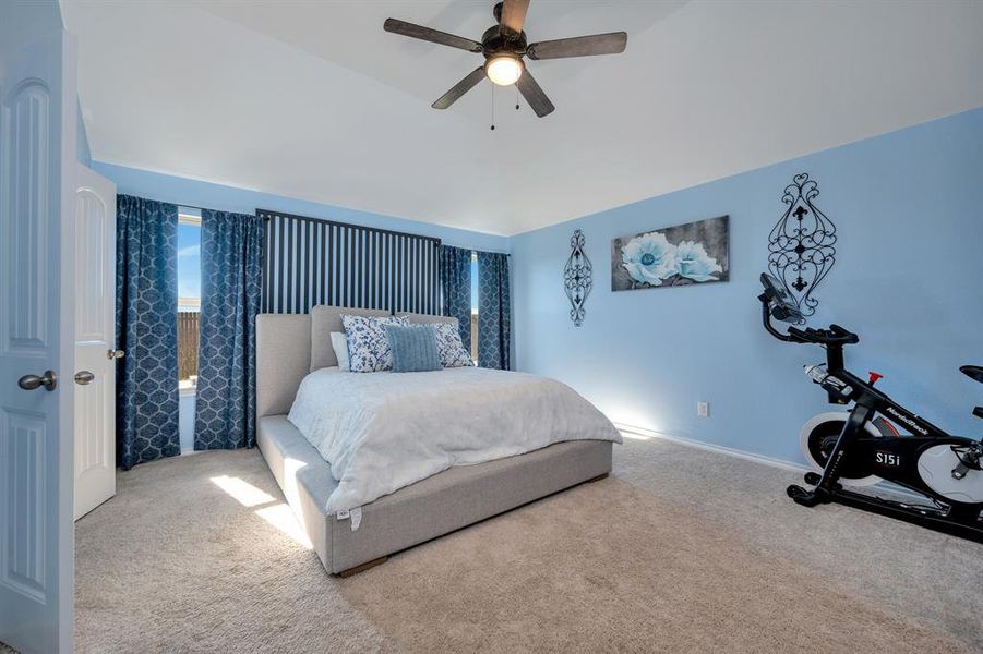 Carpeted bedroom featuring a ceiling fan and vaulted ceiling