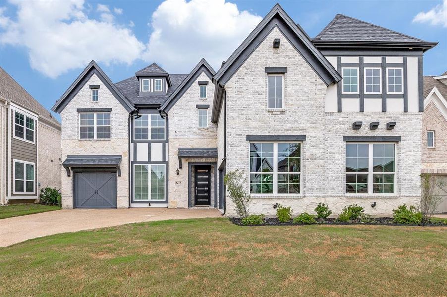 View of front facade featuring brick siding, a front lawn, driveway, and an attached garage