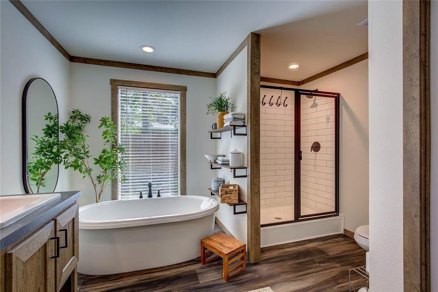 Bathroom featuring vanity, a freestanding bath, subway tile shower, ornamental molding.
