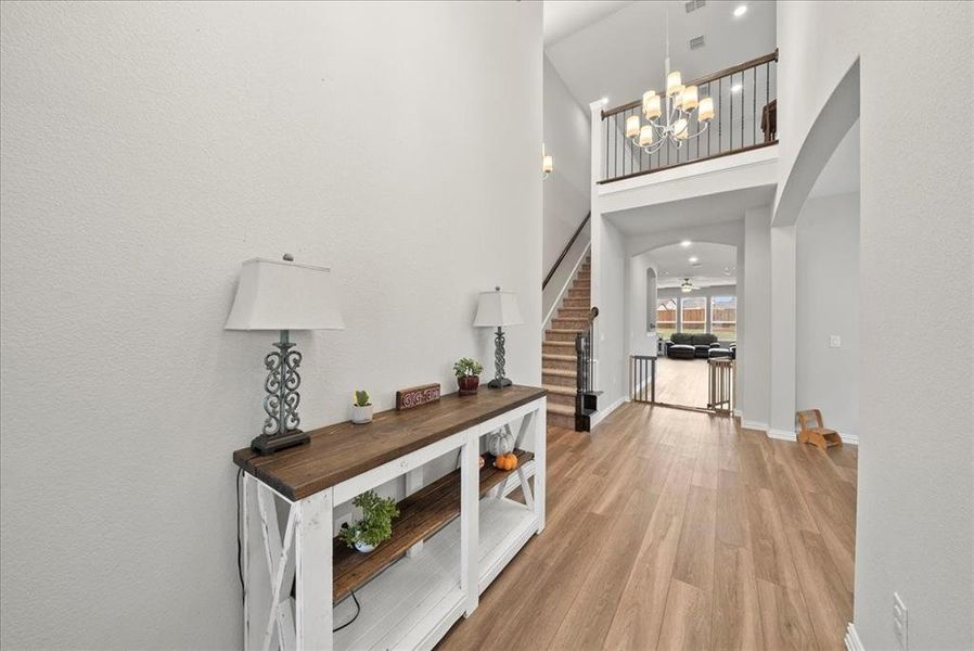 Foyer entrance featuring with notable chandeliers, a towering ceiling, and light luxury vinyl plank flooring.