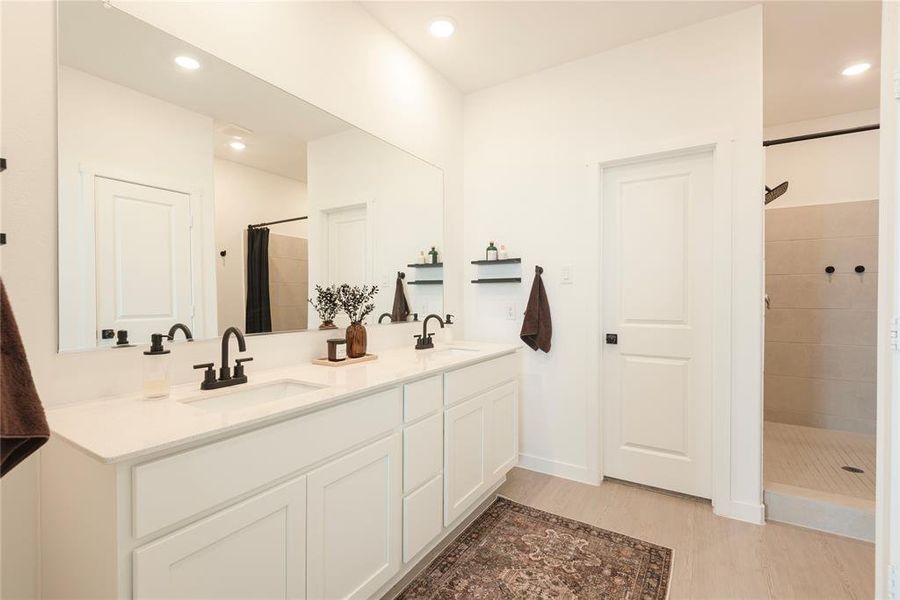 Contemporary bathroom featuring a double vanity with white cabinetry, integrated sinks, and dark-finish faucets Contemporary bathroom featuring a double vanity with white cabinetry, integrated sinks, and dark-finish faucets