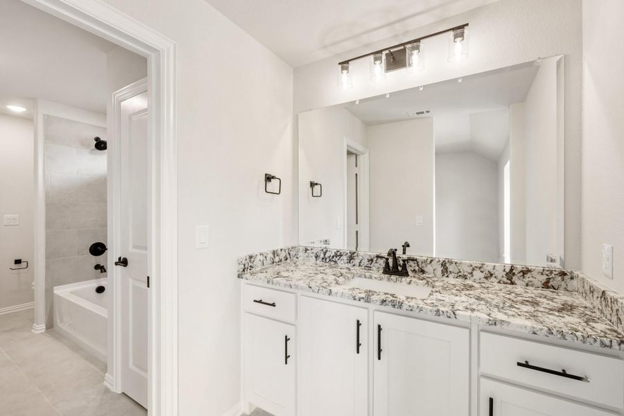 Bathroom with white cabinets, granite countertop, large mirror, and separate tub and shower area with black fixtures Bathroom with white cabinets, granite countertop, large mirror, and separate tub and shower area with black fixtures