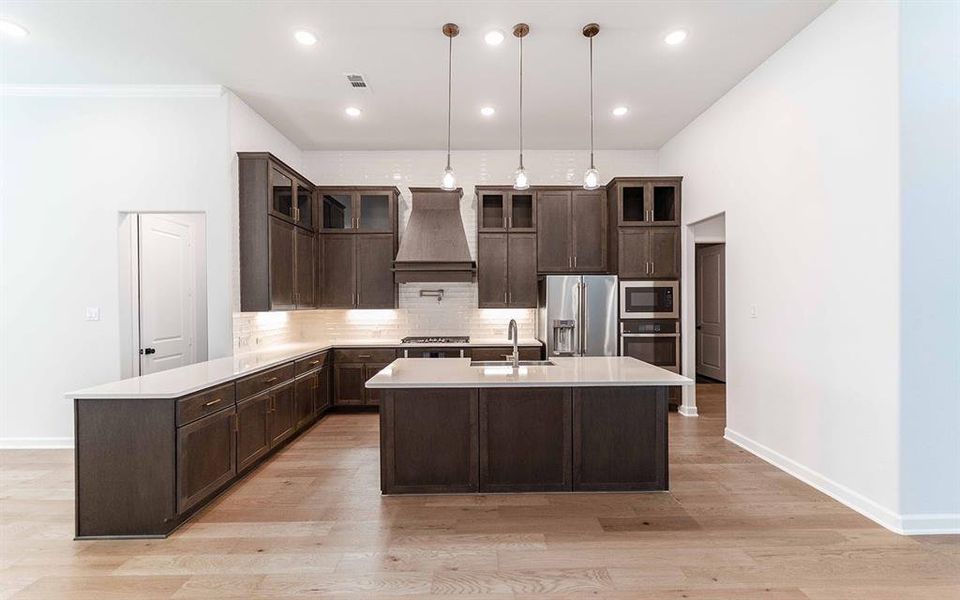 Spacious kitchen featuring dark wood cabinetry, light countertops, and wood-finish flooring Spacious kitchen featuring dark wood cabinetry, light countertops, and wood-finish flooring