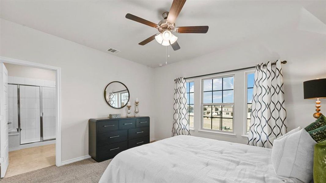 Bedroom featuring light carpet, ceiling fan, and ensuite bathroom