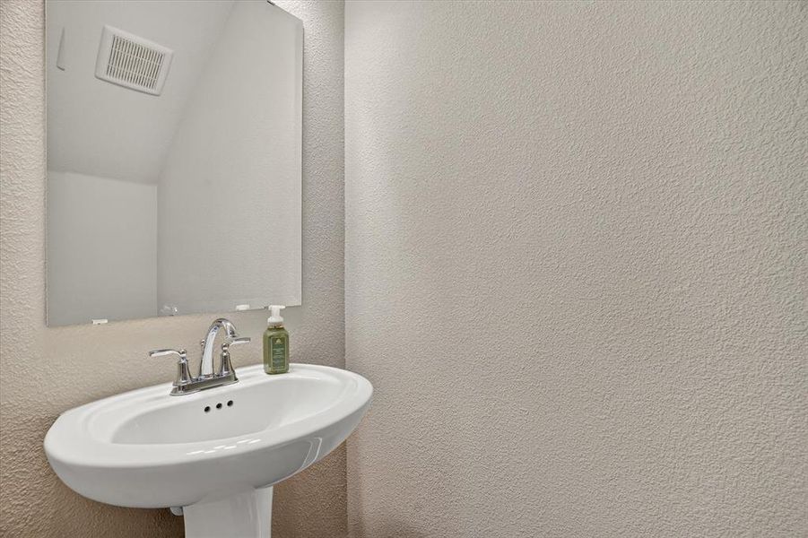 Pedestal sink with chrome faucet hardware and a frameless wall-mounted mirror Pedestal sink with chrome faucet hardware and a frameless wall-mounted mirror