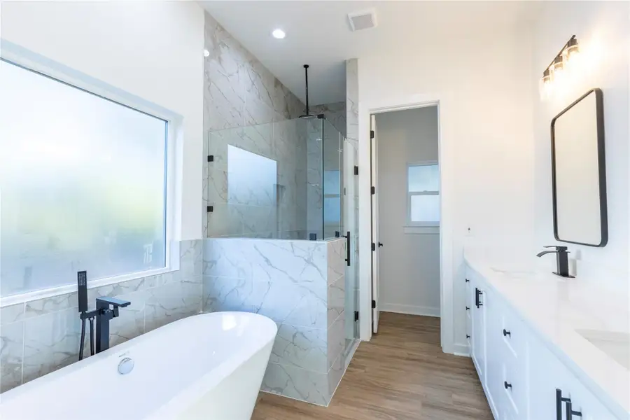 Luxurious primary bath featuring a freestanding soaking tub, spacious walk-in shower, dual vanity, and a private enclosed toilet area.