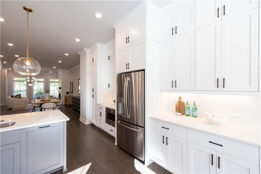 Kitchen with recessed lighting, stainless steel appliances, white cabinetry, light countertops, and pendant lighting