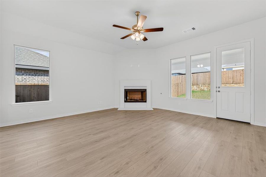 Unfurnished living room featuring a fireplace, light wood finished floors, and ceiling fan