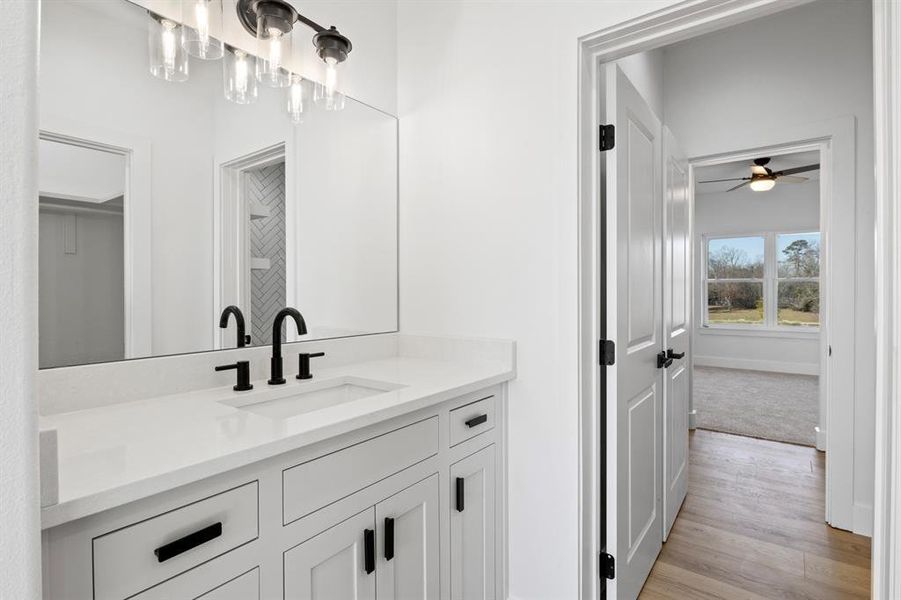 Bathroom with vanity, baseboards, wood finished floors, and ceiling fan Bathroom with vanity, baseboards, wood finished floors, and ceiling fan