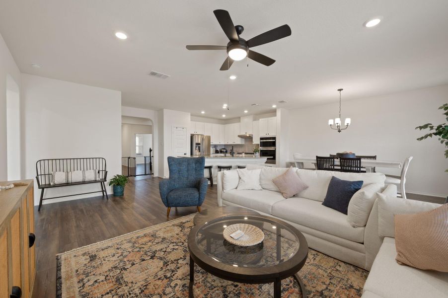 Living room with ceiling fan, dark wood finished floors, suspended lighting, and arched walkways