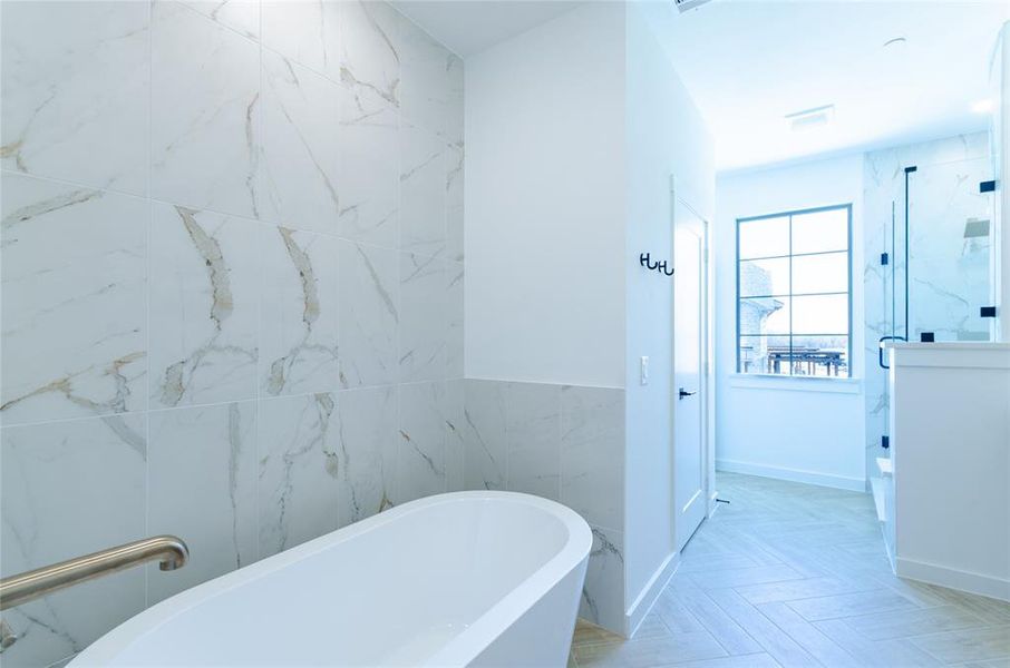 Full bath featuring a freestanding tub, tile walls, a marble finish shower, and parquet floors