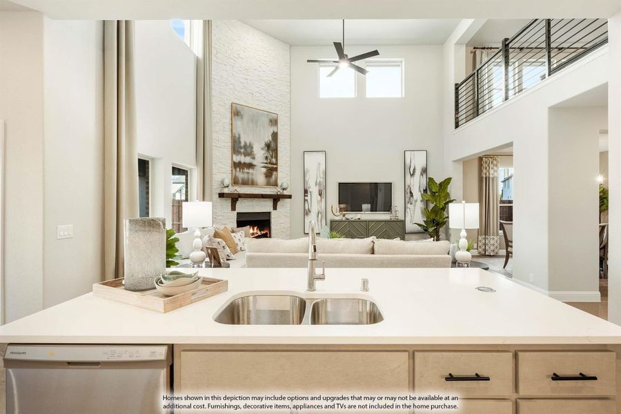 Kitchen island with double sink overlooking open-concept living room with two-story ceiling and stone fireplace