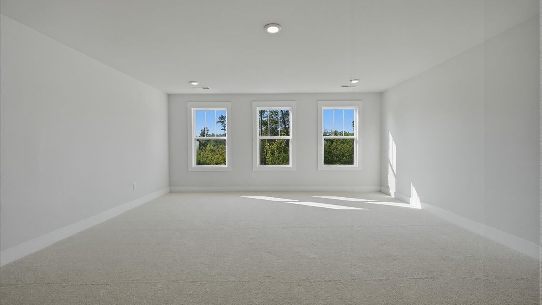 Top-notch design defines this bonus room with carpeted floors and an open, airy layout at Wells Crossing