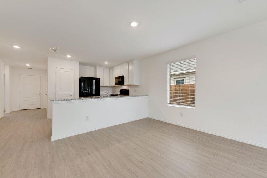 Kitchen with a peninsula, visible vents, light wood-style floors, white cabinets, and black appliances