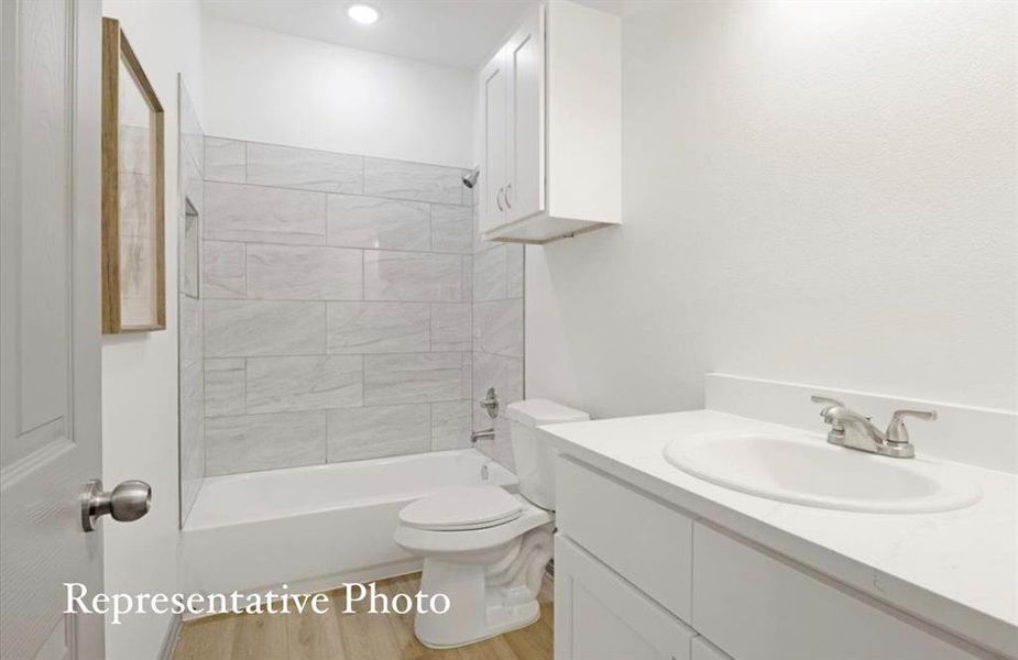 Full bathroom with wood-type flooring, vanity, toilet, and tiled shower / bath