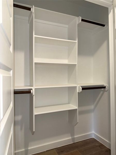 Walk in closet with dark wood finished floors