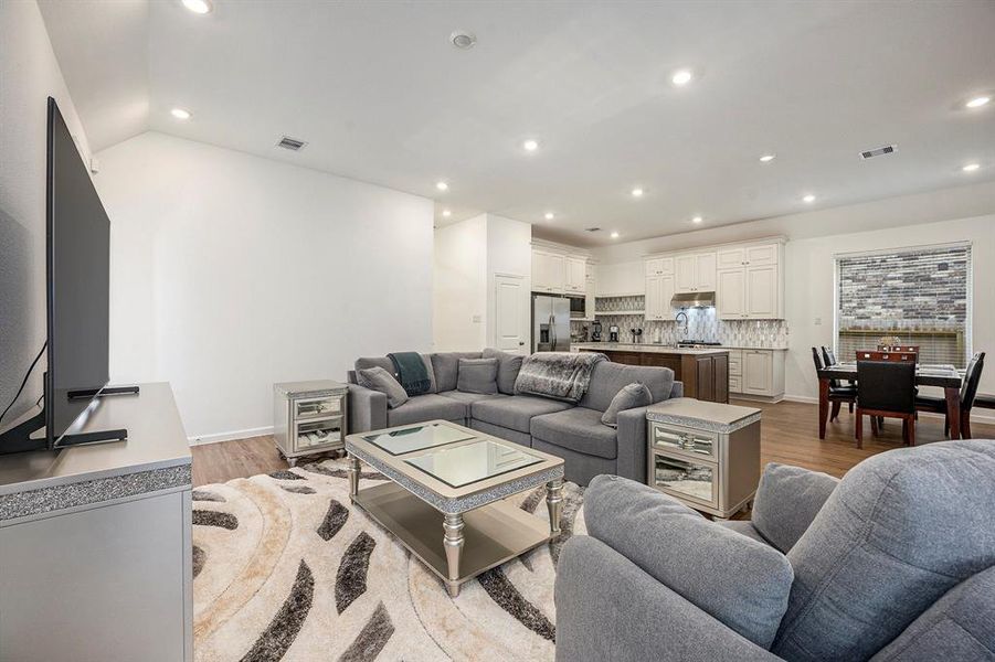 This photo showcases the modern, open-concept living area with a spacious kitchen, featuring sleek cabinetry and a tiled backsplash.