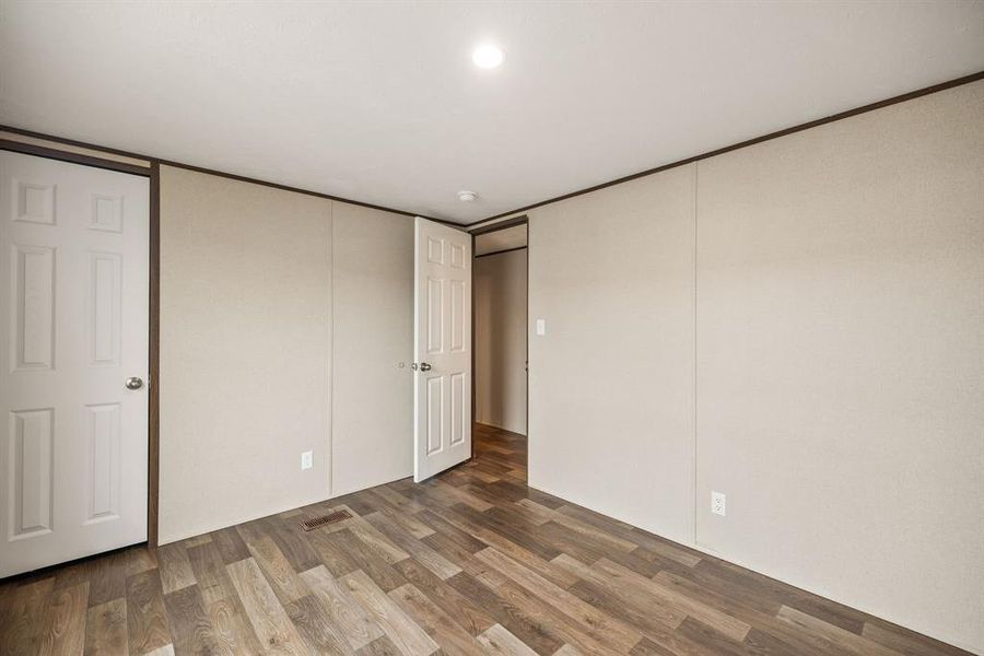 Bright interior space featuring wood-finish flooring, light-toned wall panels, and white six-panel doors Bright interior space featuring wood-finish flooring, light-toned wall panels, and white six-panel doors