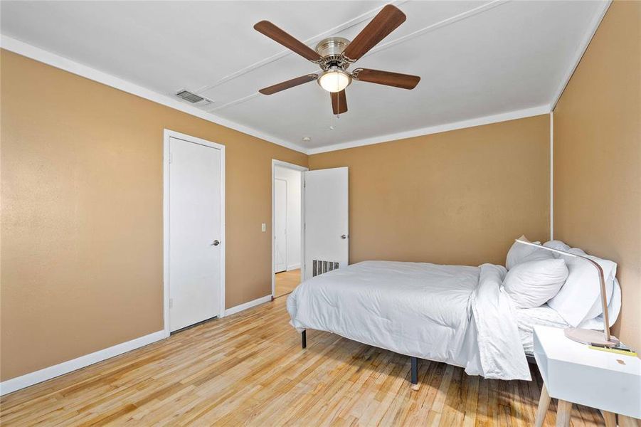 Bedroom with light wood-type flooring, ornamental molding, and a ceiling fan Bedroom with light wood-type flooring, ornamental molding, and a ceiling fan