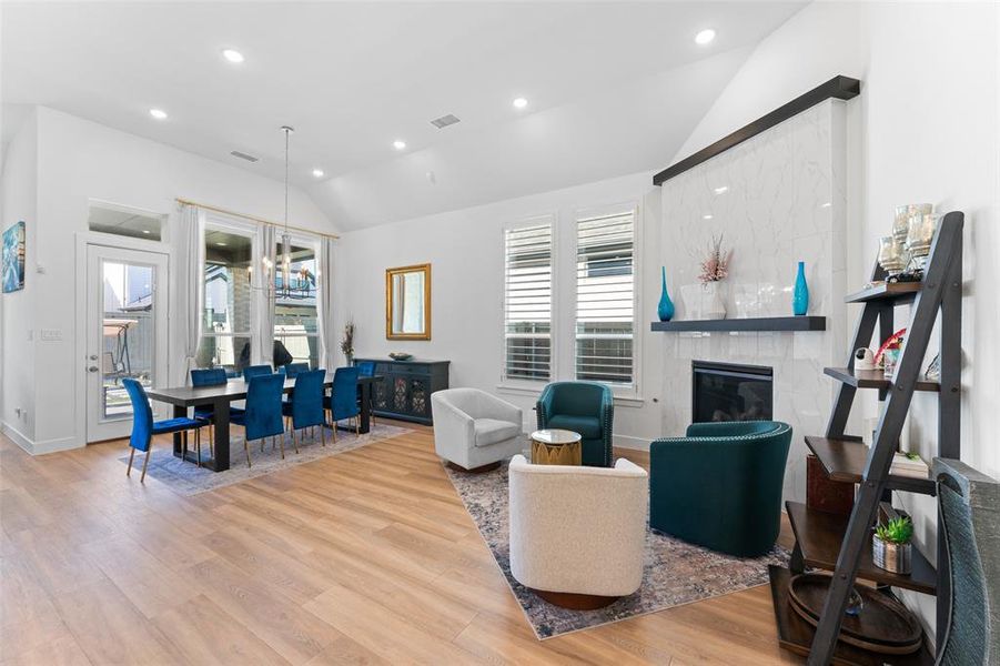 This spacious living area features high vaulted ceilings, light wood flooring, and recessed lighting throughout