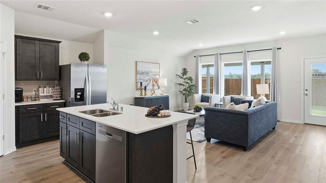 Kitchen with open floor plan, stainless steel appliances, light wood-type flooring, a breakfast bar area, and lofted ceiling