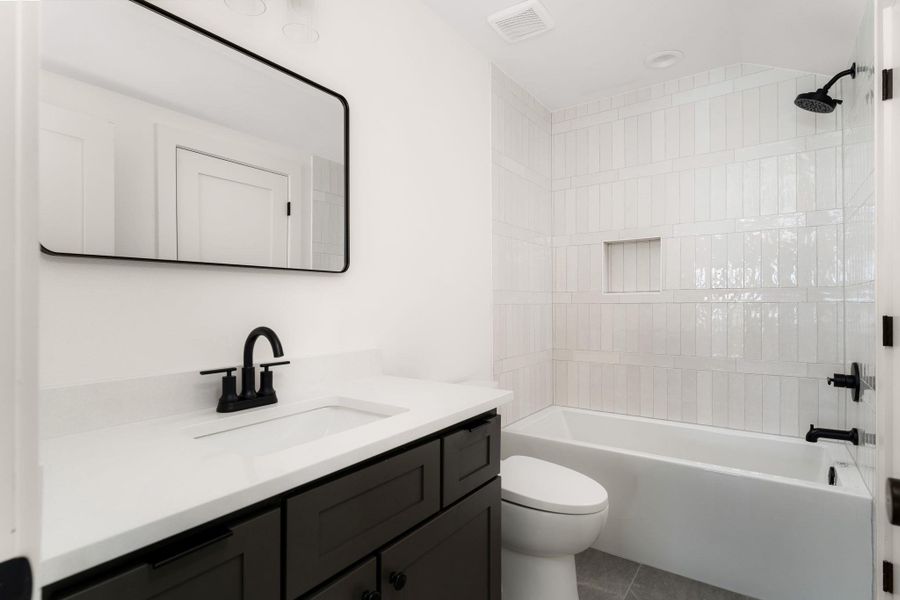 A well-appointed bath features a sleek vanity, modern fixtures, and a clean tub.