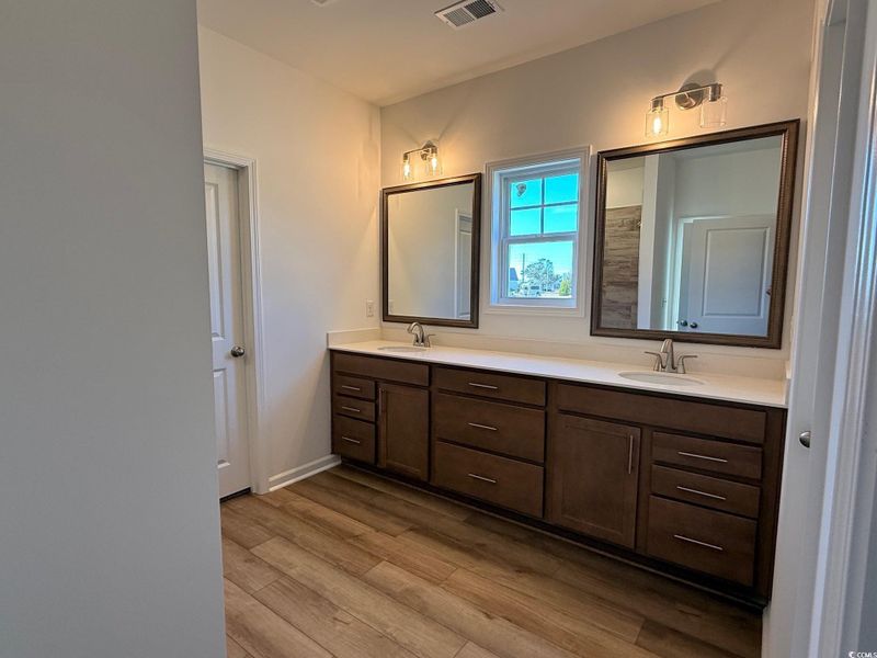 Full bathroom with double vanity, framed mirrors & light  and tile shower.
