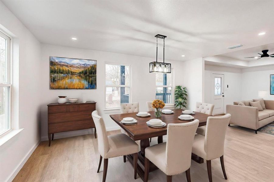 Dining space featuring a wealth of natural light, ceiling fan with notable chandelier, and light wood-type flooring